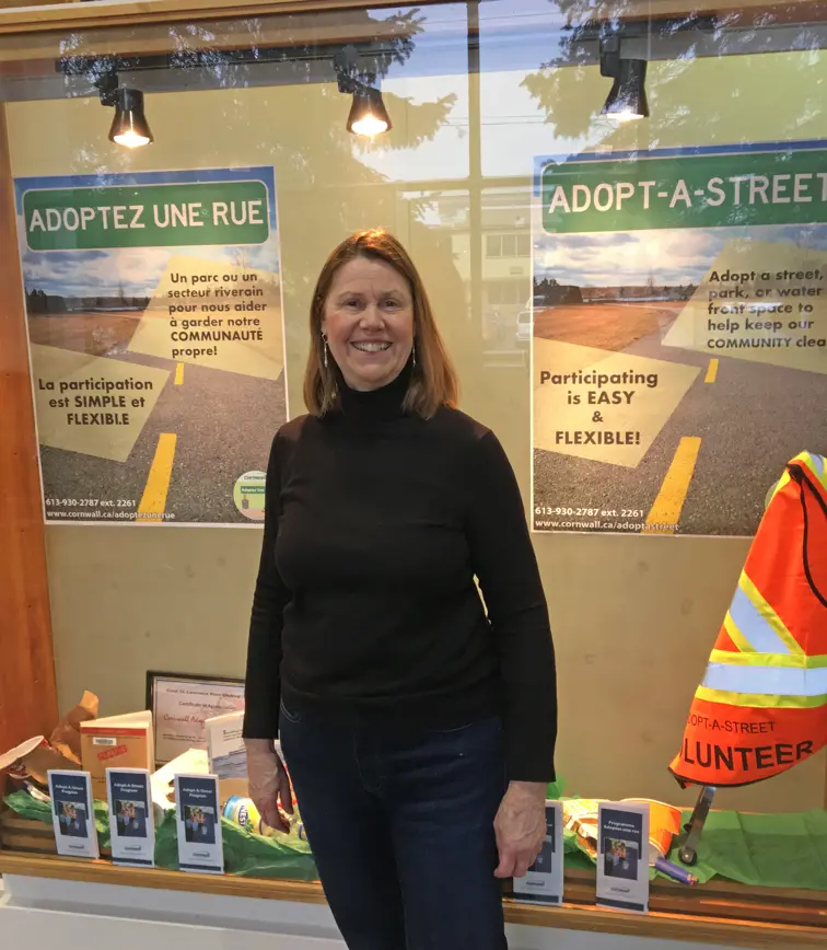 Volunteer coordinator Pam Carson stands in front of display at library.