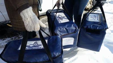 Volunteers wearing mitts holding cooler bags