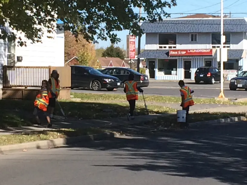 Volunteers collect litter along sidewalk.
