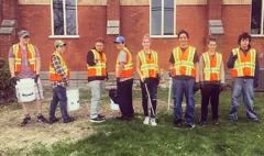 Eight students smile while volunteering.